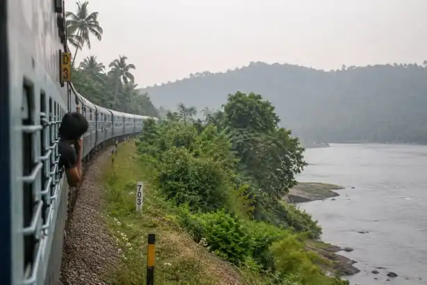 A passenger looking from a train as it curves beside a river